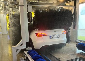 Foto eines weißen Autos in der Waschstraße, welches gerade gewaschen wird