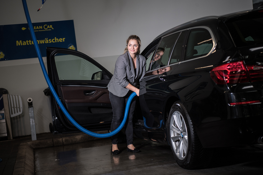 Frau in Waschstraße saugt ihr Auto sauber